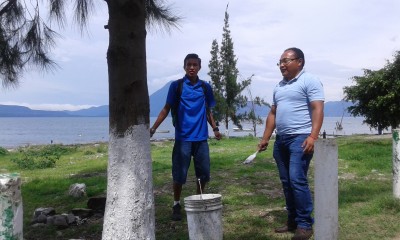 Profé Angel y Profé Marvin painting trees to help protect them from decay 